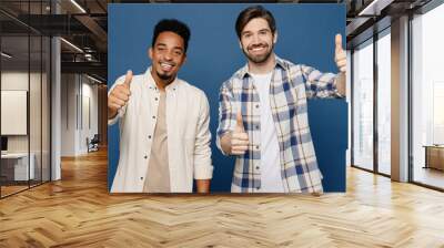 Young two friends satisfied smiling happy men 20s wear white casual shirts look camera together showing thumb up like gesture isolated plain dark royal navy blue background. People lifestyle concept. Wall mural