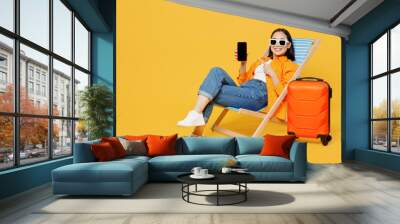 Young woman in summer clothes sit in deckchair use blank screen mobile cell phone isolated on plain yellow background Tourist travel abroad in free time rest getaway. Air flight trip journey concept Wall mural