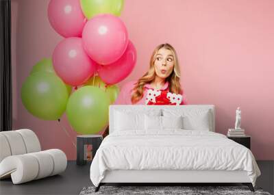 Young woman wear shirt celebrating birthday holiday and hold bunch of colorful air balloons hold present box with gift ribbon bow look aside isolated on plain pastel pink background Lifestyle concept Wall mural