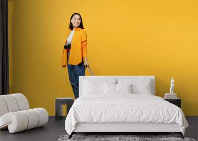 Young woman wear summer casual clothes walk go with suitcase bag look aside isolated on plain yellow background. Tourist travel abroad in free spare time rest getaway. Air flight trip journey concept. Wall mural