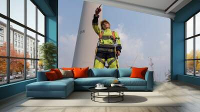 Female engineer standing against turbines on wind turbine farm.	 Wall mural