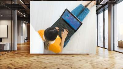 Top view of a young woman holding laptop computer on her lap while sitting at home Wall mural