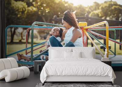 Woman, young girl together on roundabout at park and playing with smile and fun outdoor. Love, care and bonding with family happiness, mother and daughter enjoying time at playground with freedom Wall mural