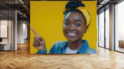 A smiling woman wearing a bright yellow headband points towards the camera Wall mural