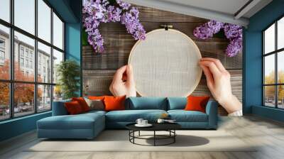 A woman holding a white embroidery on a wooden surface Wall mural