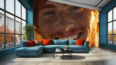 This close-up depicts a beaming young man with freckles, his genuine, wide smile radiating warmth and joy. Wall mural