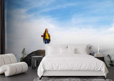 young tourist girl on huge rock with big puddle in the middle under beautiful blue sky enjoying fantastic view of mountains outstretched arms Wall mural