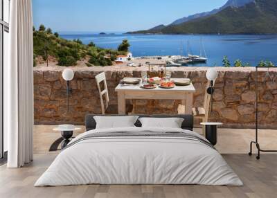 a table served for two with snacks and drinks on the summer terrace of the hotel room by the seascap Wall mural