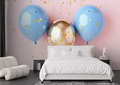 Three balloons, two blue and one gold, surrounded by scattered confetti on a pink background, celebrating a festive occasion. Wall mural