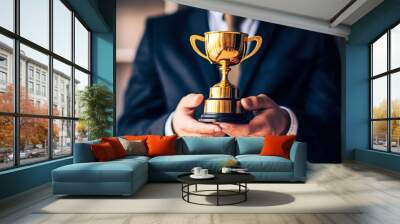 Hand of a Businessman Holding a Golden Trophy. Achievement and business goal success concept, winner and success of business, businessman holding cup of leadership trophy success Wall mural