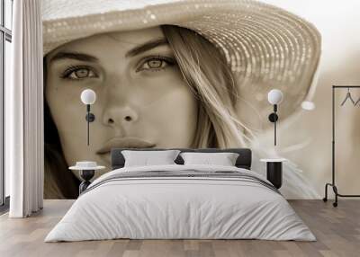  A black-and-white image of a woman in a straw hat, gazing intently at the camera with a serious expression Wall mural