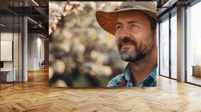  A man in a straw hat stands before a tree, its white flowers contrasting against the background He carries a brown bag over his shoulder Wall mural