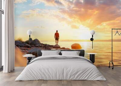  A person on a rock amidst tranquil water as the sun sets behind them Wall mural