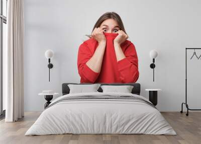 A girl with a social phobia hides her face in a sweater. She looks frightened at the camera Wall mural