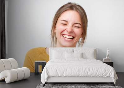 Beautiful young woman in yellow sweater laughing against white background. Wall mural