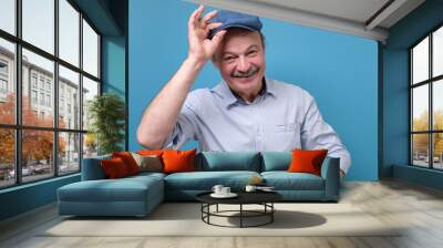 Cheerful senior man greets by taking off a hat Wall mural