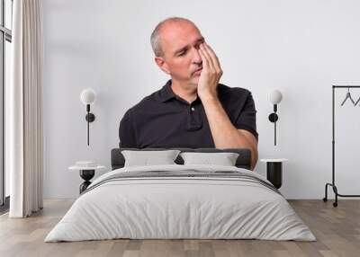 Closeup portrait of mature man wearing black shirt with tooth ache isolated on gray background. Concept of dental problems and healthcare Wall mural