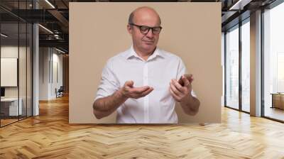 Elderly caucasian man frowns and looks at the smartphone receiving unexpected news on sms. Studio shot Wall mural