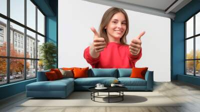 Happy smiling beautiful young woman showing thumbs up gesture Wall mural