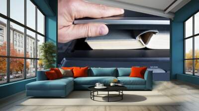 man hands putting a book into a copying device Wall mural