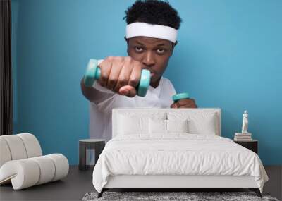 Smiling young african american guy training with dumbbells. Wall mural