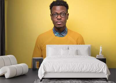 Young african american man in yellow sweater looking serious at camera. Studio shot Wall mural