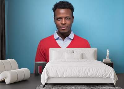 Young african man smiling at camera isolated on blue background. Studio shot. Wall mural