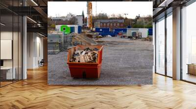 Orange metal container for collecting waste and stacked scaffolding at a construction site. Wall mural