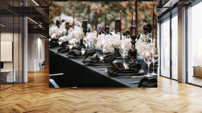 Serving and decorating a banquet table in black with white flowers and black candles at an outdoor party. Wall mural