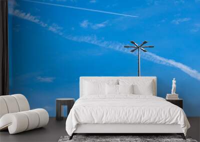 Vertical metal mast with lighting lanterns against a background of blue sky with light clouds. Wall mural