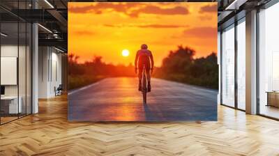 silhouette of cyclist man riding a bike bicycle on asphalt road at orange twilight dusk sunset sky Wall mural