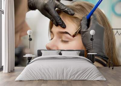 Beautiful woman drawing a shape of eyebrows using cosmetic brush. Make up artist applying make up to a model Wall mural