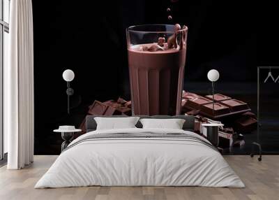 Chocolate milk in glass and chocolate pieces on dark background Wall mural