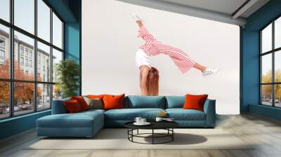 Inclusive Beauty. Girl with red hair isolated on grey doing front handspring Wall mural