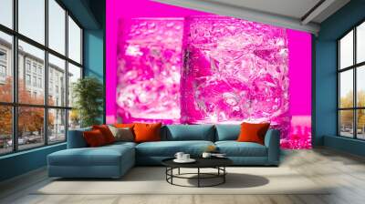 Glass with water and ice over pink Wall mural