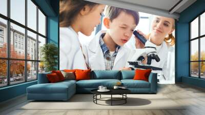 Little kids with teacher in school laboratory looking in microscope close-up Wall mural