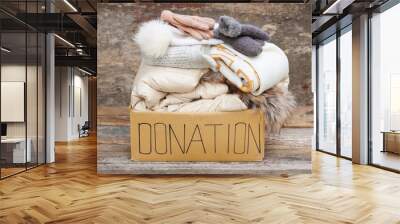 Donation box with winter clothes on an old wooden background. Wall mural