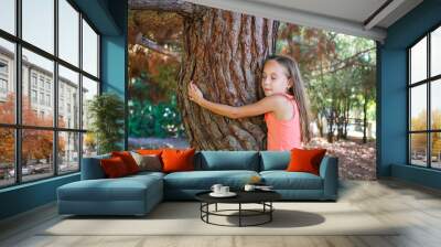 Girl hugging tree in park. Wall mural