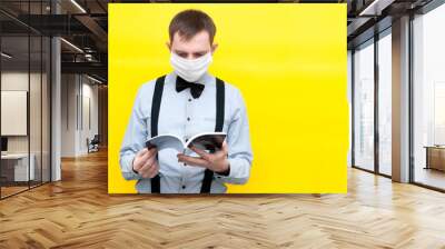 man in white medical face mask readind blue brochure with usa constitution in front of yellow background with copy space Wall mural