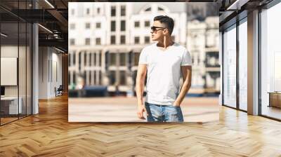 Outdoors Leisure. Stylish guy in sunglasses standing on the street hand in pocket looking aside pensive Wall mural