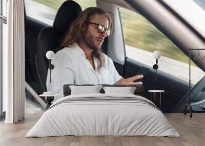 Young adult man using smartphone, sitting in car Wall mural