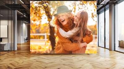 Young adult mother hugging her child girl outdoor Wall mural