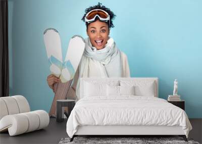 young african woman isolated on blue wall studio winter sport skiing Wall mural