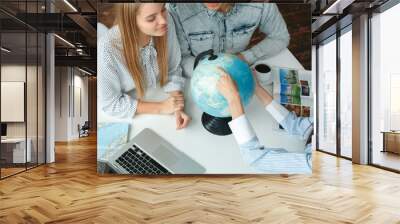 Young couple in a tour agency communication with a travel agent travelling concept destination on a globe Wall mural