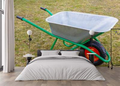 Garden metal wheelbarrow with green reinforced frame on one wheel in the garden Wall mural