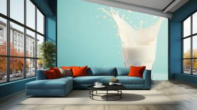 Milk flowing into a glass with an elegant splash effect, complemented by a light blue background Wall mural