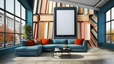 High-quality stock photo of a black ebook reader surrounded by various paper books Wall mural