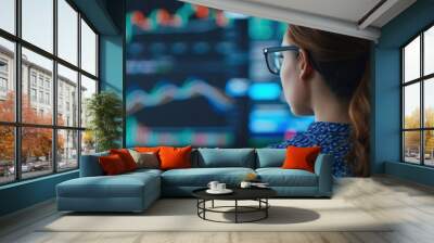 A woman in glasses carefully studies multiple financial screens displaying stock market data and graphs, analyzing trends and performance. Wall mural