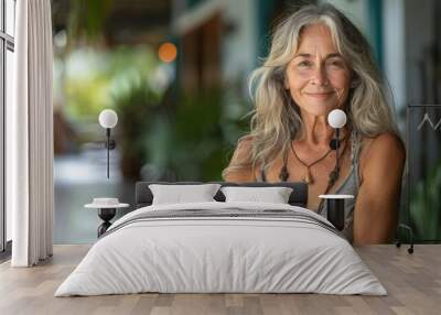 Portrait of a beautiful mature woman with long gray hair and a warm smile, wearing a gray and white printed dress Wall mural