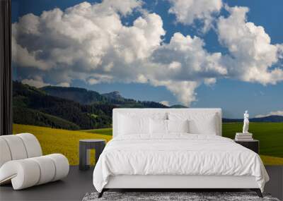 Spring landscape with fields of oilseed rape. Hills and blue sky with dramatic clouds in the background. The Klak hill from The Rajecka valley in Slovakia, Europe. Wall mural